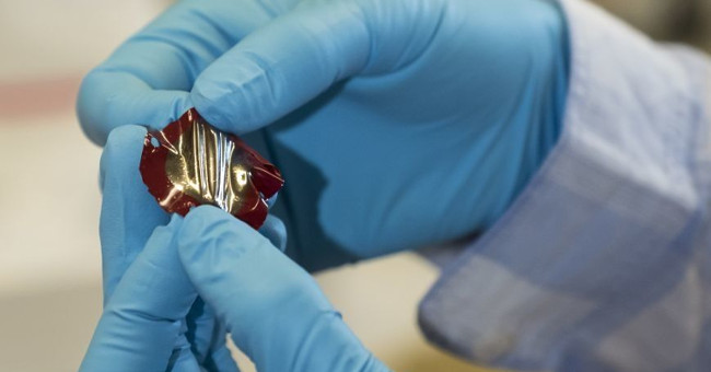 Create a super-elastic material that can generate electricity when pulled or compressed