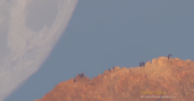 The illusion of the Moon falling behind the volcano peak