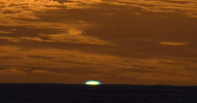 The sun shines green light on the sea