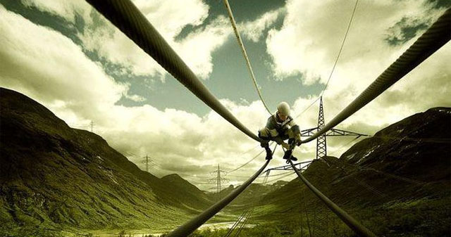 Heart-stopping scene at the scene of a man sitting on a helicopter, holding a metal rod near a high-voltage wire